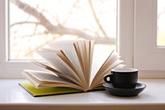 Een open boek op het venster en een koffiekop stock foto Een open boek op het venster en een koffiekop stock foto