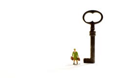 Een oude sleutel op een witte achtergrond met een miniatuurreiziger stock fotografie Een oude sleutel op een witte achtergrond met een miniatuurreiziger stock fotografie