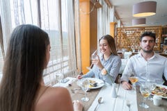 Een paar met een vrouwelijke vriend die gesprek in een restauran hebben stock foto's Een paar met een vrouwelijke vriend die gesprek in een restauran hebben stock foto's