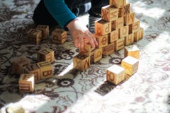 Een piramide van houten blokken en het concept een tijd-KLEINE jongen die van kinderen op de vloer spelen stock foto Een piramide van houten blokken en het concept een tijd-KLEINE jongen die van kinderen op de vloer spelen stock foto