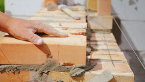 Een professionele arbeider zet de baksteen in het metselwerk stock afbeelding Een professionele arbeider zet de baksteen in het metselwerk stock afbeelding