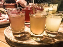 Een reeks veel heerlijke geeloranje rode glazen, schoten met sterke alcohol, wodka, het vullen, brandewijn op houten tribunes stock afbeeldingen Een reeks veel heerlijke geeloranje rode glazen, schoten met sterke alcohol, wodka, het vullen, brandewijn op houten tribunes stock afbeeldingen