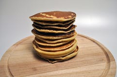 Een stapel van ronde gouden pannekoeken op een houten tribune stock afbeelding Een stapel van ronde gouden pannekoeken op een houten tribune stock afbeelding