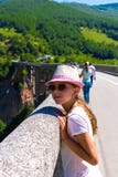 Een tiener in een hoed en glazen op de brug die uit in de afstand tegen de achtergrond van de bergen kijken stock fotografie Een tiener in een hoed en glazen op de brug die uit in de afstand tegen de achtergrond van de bergen kijken stock fotografie
