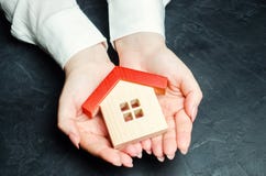 Een vrouw beschermt een miniatuurblokhuis met een rood dak Het concept van de bezitsverzekering Bescherming van huisvesting Veili royalty-vrije stock fotografie Een vrouw beschermt een miniatuurblokhuis met een rood dak Het concept van de bezitsverzekering Bescherming van huisvesting Veili royalty-vrije stock fotografie