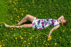Een vrouw in een katoenen kleding ligt op het groene gras met paardebloemen royalty-vrije stock foto's Een vrouw in een katoenen kleding ligt op het groene gras met paardebloemen royalty-vrije stock foto's