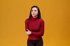Een vrouw in een rode col houdt haar maag Het meisje heeft een maagpijn Van strenge pijn wil de mooie jonge vrouw schreeuwen royalty-vrije stock foto Een vrouw in een rode col houdt haar maag Het meisje heeft een maagpijn Van strenge pijn wil de mooie jonge vrouw schreeuwen royalty-vrije stock foto