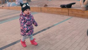 Een weinig zoet meisje in een kleurrijk roze jasje dat mamma verzoekt dichtbij een speelplaats in een park op de rand van het bos stock footage Een weinig zoet meisje in een kleurrijk roze jasje dat mamma verzoekt dichtbij een speelplaats in een park op de rand van het bos stock footage