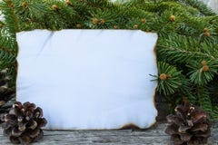 Een wit blad van document brandde langs de randen en de groene takken van een Kerstboom op de achtergrond van oude, houten raad stock foto's Een wit blad van document brandde langs de randen en de groene takken van een Kerstboom op de achtergrond van oude, houten raad stock foto's