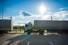 Een witte semi vrachtwagen met de ritten van een ladingsaanhangwagen in het parkeerterrein en geparkeerd met andere voertuigen Wa royalty-vrije stock afbeelding Een witte semi vrachtwagen met de ritten van een ladingsaanhangwagen in het parkeerterrein en geparkeerd met andere voertuigen Wa royalty-vrije stock afbeelding