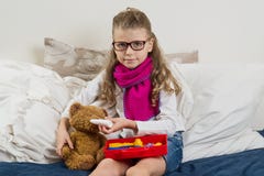 Een Ziek kindmeisje in glazen, heelt zijn zieke Teddybeer royalty-vrije stock afbeelding Een Ziek kindmeisje in glazen, heelt zijn zieke Teddybeer royalty-vrije stock afbeelding