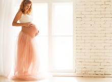 Een zwangere vrouw in een witte bovenkant en Tulle begrenzen tribunes dichtbij een groot venster stock foto's Een zwangere vrouw in een witte bovenkant en Tulle begrenzen tribunes dichtbij een groot venster stock foto's