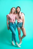 Eenage flickvänner, caucasian kvinna och asiatkvinna - som isoleras på blå bakgrund arkivfoto Eenage flickvänner, caucasian kvinna och asiatkvinna - som isoleras på blå bakgrund arkivfoto