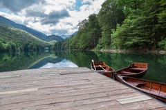 Eevergreen forest on the Biogradskoe lake from wooden pier with rowboat. Biogradska Gora national park. Montenegro, Europa royalty free stock image Eevergreen forest on the Biogradskoe lake from wooden pier with rowboat. Biogradska Gora national park. Montenegro, Europa royalty free stock image