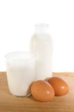 Eggs and milk in glass and bottle. Brown eggs and some milk in glass and bottle on white stock photos Eggs and milk in glass and bottle. Brown eggs and some milk in glass and bottle on white stock photos
