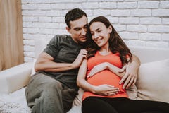 Ehemann und schwangere Frau, die auf Couch sich entspannen stockfotografie Ehemann und schwangere Frau, die auf Couch sich entspannen stockfotografie