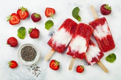 Eigengemaakte de kokosmelkijslollys van de veganistaardbei met chiazaden op rustieke witte achtergrond Stock Fotografie Eigengemaakte de kokosmelkijslollys van de veganistaardbei met chiazaden op rustieke witte achtergrond Stock Fotografie