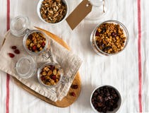 Eigengemaakte granola met noten en vruchten in glaskruiken op witte linnenachtergrond Hoogste mening stock fotografie Eigengemaakte granola met noten en vruchten in glaskruiken op witte linnenachtergrond Hoogste mening stock fotografie