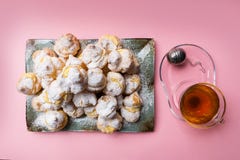 Eigengemaakte profiteroles dienden op een plaat met een kop thee op een roze achtergrond Vlak leg stock foto Eigengemaakte profiteroles dienden op een plaat met een kop thee op een roze achtergrond Vlak leg stock foto
