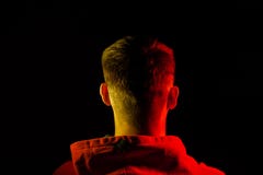 Ein erwachsener Mann steht zur?ck und Hals in einem orange mit Kapuze Sweatshirt, das in Rotem und in Gelbem auf den Seiten mit e stockbild Ein erwachsener Mann steht zur?ck und Hals in einem orange mit Kapuze Sweatshirt, das in Rotem und in Gelbem auf den Seiten mit e stockbild
