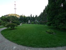 Ein grüner Rasen im Park mit einem Weg um ihn führend zu einen kleinen Gazebo mit einer Skulptur lizenzfreies stockfoto Ein grüner Rasen im Park mit einem Weg um ihn führend zu einen kleinen Gazebo mit einer Skulptur lizenzfreies stockfoto