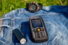 Ein Handy und eine Energie haben auf Jeans auf Hintergrunduhr ein Bankkonto lizenzfreies stockbild Ein Handy und eine Energie haben auf Jeans auf Hintergrunduhr ein Bankkonto lizenzfreies stockbild
