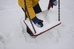 Ein Junge sammelt Schnee mit einem Schwingen im Park lizenzfreies stockbild Ein Junge sammelt Schnee mit einem Schwingen im Park lizenzfreies stockbild