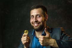 Ein junger Geschäftsmann hält eine Münze von bitcoite in seiner Hand lizenzfreie stockbilder Ein junger Geschäftsmann hält eine Münze von bitcoite in seiner Hand lizenzfreie stockbilder