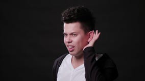 Ein junger Mann, der gegen einen schwarzen Hintergrund mimicing ist lizenzfreies stockbild Ein junger Mann, der gegen einen schwarzen Hintergrund mimicing ist lizenzfreies stockbild