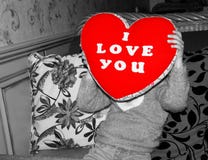 ein Kind bedeckt ihr Gesicht mit einem weichen Kissen in Form eines Herzens mit ich liebe dich gestickt stockfoto ein Kind bedeckt ihr Gesicht mit einem weichen Kissen in Form eines Herzens mit ich liebe dich gestickt stockfoto