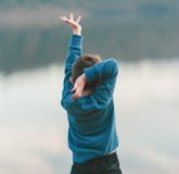 Ein kleiner Junge tanzt gegen einen Flusshintergrund lizenzfreies stockbild Ein kleiner Junge tanzt gegen einen Flusshintergrund lizenzfreies stockbild