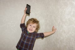 Ein kleiner Kleinkindjunge hebt ein Smartphonegerät über seinem Kopf auf lizenzfreie stockbilder Ein kleiner Kleinkindjunge hebt ein Smartphonegerät über seinem Kopf auf lizenzfreie stockbilder
