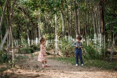 Ein kleiner netter Junge in der Weinlesekleidung und ein kleines schönes Mädchen in einem Retro- Kleid gehen im Wald und machen F stockbilder Ein kleiner netter Junge in der Weinlesekleidung und ein kleines schönes Mädchen in einem Retro- Kleid gehen im Wald und machen F stockbilder