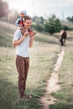 Ein kleiner Sohn sitzt auf den Schultern seines Vatis und ein Pferd ist im Hintergrund lizenzfreie stockfotos Ein kleiner Sohn sitzt auf den Schultern seines Vatis und ein Pferd ist im Hintergrund lizenzfreie stockfotos
