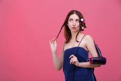 Ein kokettes Mädchen, in einem Bad, mit Haarlockenwicklern, zusammengedrückte Lippen, schaut oben und spielt mit einer Locke des lizenzfreies stockfoto Ein kokettes Mädchen, in einem Bad, mit Haarlockenwicklern, zusammengedrückte Lippen, schaut oben und spielt mit einer Locke des lizenzfreies stockfoto