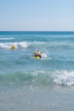 Ein Leibwächter, der auf der Surfbrettrettung für einen Notfall schwimmt lizenzfreie stockfotografie Ein Leibwächter, der auf der Surfbrettrettung für einen Notfall schwimmt lizenzfreie stockfotografie
