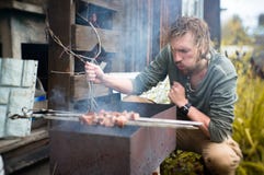 Ein Mann brät Kebabs auf Mongal in seinem Gartenplan lizenzfreie stockfotografie Ein Mann brät Kebabs auf Mongal in seinem Gartenplan lizenzfreie stockfotografie