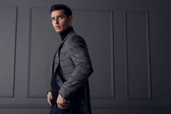Ein Mann in einer Schal-grauen Jacke und in einem Rollkragen, stehend im Profil mit den Händen in seinen Taschen und schauen über stockbilder Ein Mann in einer Schal-grauen Jacke und in einem Rollkragen, stehend im Profil mit den Händen in seinen Taschen und schauen über stockbilder
