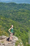 Ein Mädchen steht auf einer Klippe vor dem hintergrund des grünen Waldes stockfotos Ein Mädchen steht auf einer Klippe vor dem hintergrund des grünen Waldes stockfotos