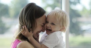 Ein nettes blondes Kind umarmt eine junge Mutter in der Front durch das große Fenster stock video Ein nettes blondes Kind umarmt eine junge Mutter in der Front durch das große Fenster stock video