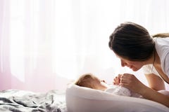 Ein neugeborenes Baby liegt auf dem Bett und die Mutter h?lt seine H?nde lizenzfreie stockfotografie Ein neugeborenes Baby liegt auf dem Bett und die Mutter h?lt seine H?nde lizenzfreie stockfotografie