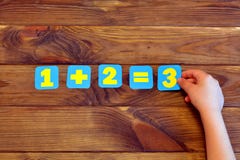 Ein plus zwei Gleichgestellte drei Ein mathematisches Beispiel Kind hält eine Papierzahl Brown-hölzerner Hintergrund stockfotos Ein plus zwei Gleichgestellte drei Ein mathematisches Beispiel Kind hält eine Papierzahl Brown-hölzerner Hintergrund stockfotos