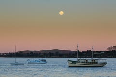 Ein Vollmond, der über Boote in einem Hafen steigt lizenzfreies stockbild Ein Vollmond, der über Boote in einem Hafen steigt lizenzfreies stockbild