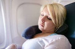 Eine blonde junge erwachsene Frau benutzt ein Halskissen, um auf einem langen Flugzeugflug zu schlafen und Nickerchen zu machen F lizenzfreie stockbilder Eine blonde junge erwachsene Frau benutzt ein Halskissen, um auf einem langen Flugzeugflug zu schlafen und Nickerchen zu machen F lizenzfreie stockbilder