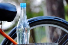 Eine Flasche Trinkwasser auf einem alten Bauholz am Park mit verwischt einem Fahrradparken auf dem Erdgeschoss stockfoto Eine Flasche Trinkwasser auf einem alten Bauholz am Park mit verwischt einem Fahrradparken auf dem Erdgeschoss stockfoto