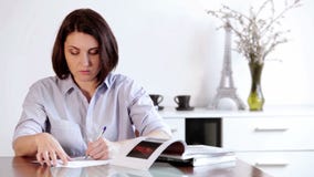 Eine Frau sitzt am Tisch und schreibt etwas mit einem ballpen stock video Eine Frau sitzt am Tisch und schreibt etwas mit einem ballpen stock video