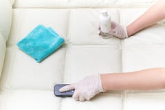 Eine Frau säubert das lederne Sofa mit einer Bürste und einem Reinigungsmittel lizenzfreie stockbilder Eine Frau säubert das lederne Sofa mit einer Bürste und einem Reinigungsmittel lizenzfreie stockbilder