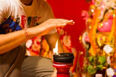 Eine Hand, die Hitze der Flamme als Segen von einer beleuchteten Lehmlampe auf ein Lehmstand- oder -anbetungsidol durgapuja Indie lizenzfreies stockbild Eine Hand, die Hitze der Flamme als Segen von einer beleuchteten Lehmlampe auf ein Lehmstand- oder -anbetungsidol durgapuja Indie lizenzfreies stockbild