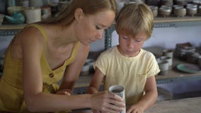 Eine junge Frau und ihr weniger Sohn auf einer Tonwarenvorlagenklasse stock footage Eine junge Frau und ihr weniger Sohn auf einer Tonwarenvorlagenklasse stock footage
