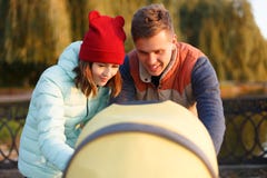 Eine junge liebevolle Familie geht durch den See mit einem Spaziergänger Lächelnde Elternpaare mit Baby Pram im Herbstpark unters Stockbilder Eine junge liebevolle Familie geht durch den See mit einem Spaziergänger Lächelnde Elternpaare mit Baby Pram im Herbstpark unters Stockbilder